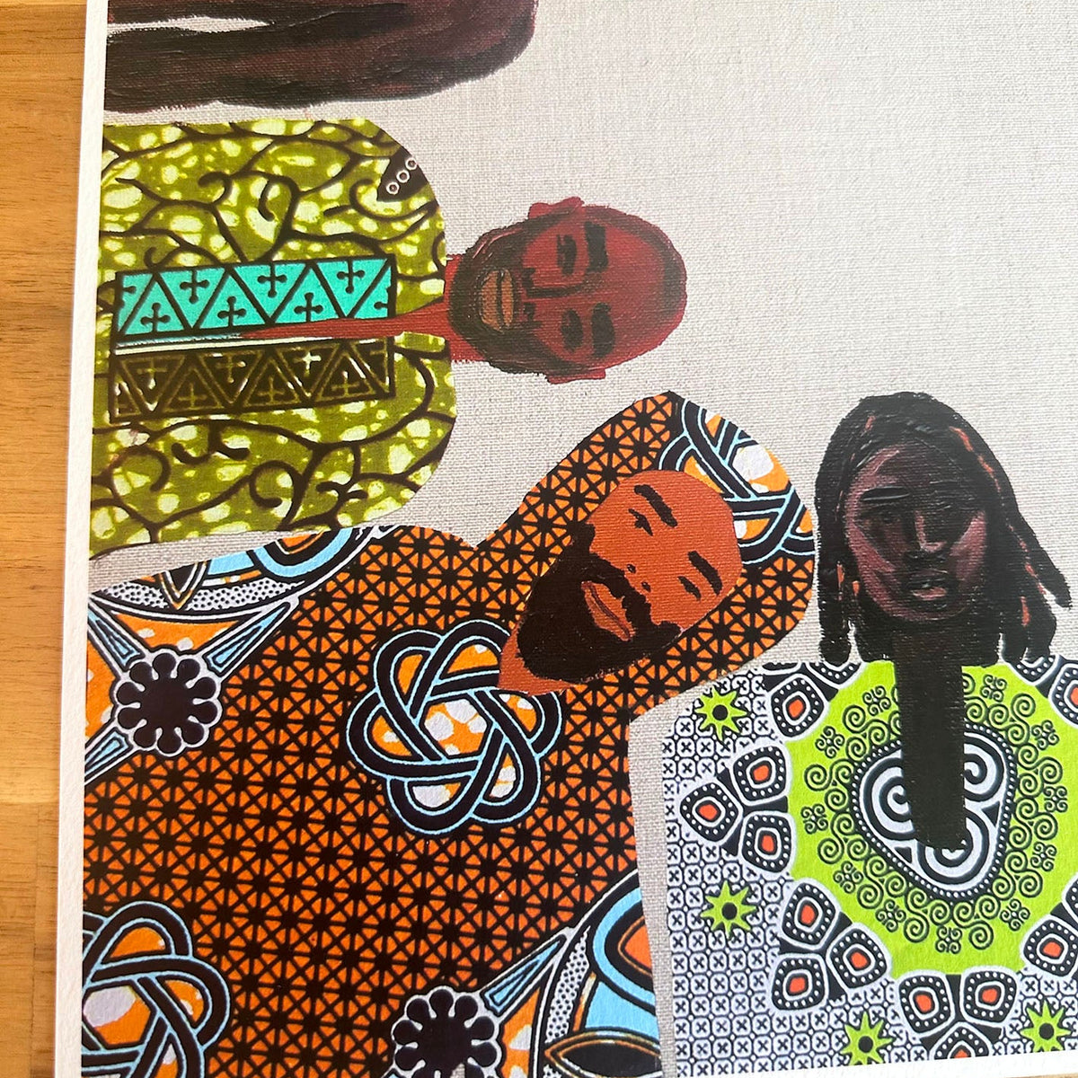 A square art print featuring a collage of stylized portraits of men in vibrant African wax print patterns, close up corner detail. 