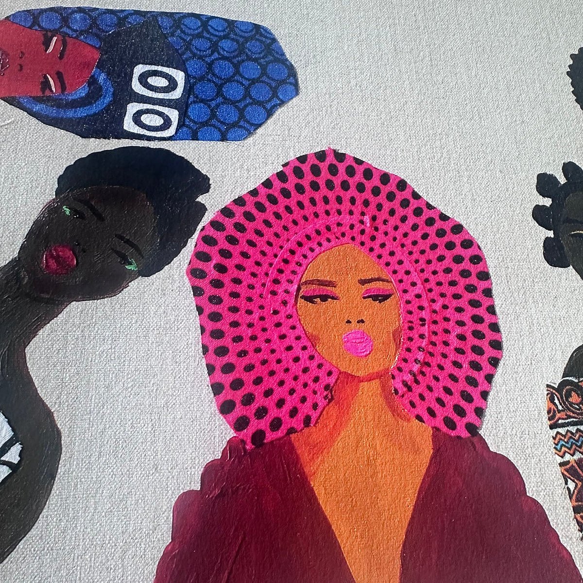A close-up of a colorful art print or painting featuring stylized illustrated women with bold patterns, including a central figure with a bright pink dotted head covering and dark red clothing on a light background.